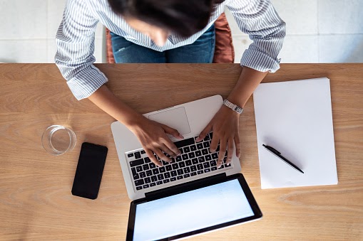 Woman typing on a laptop.