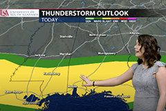 Female student giving weather announcement in front of green screen.