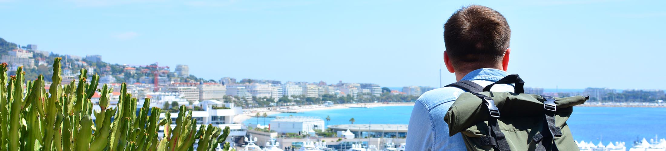 Male wearing backpack and looking out over shoreline.