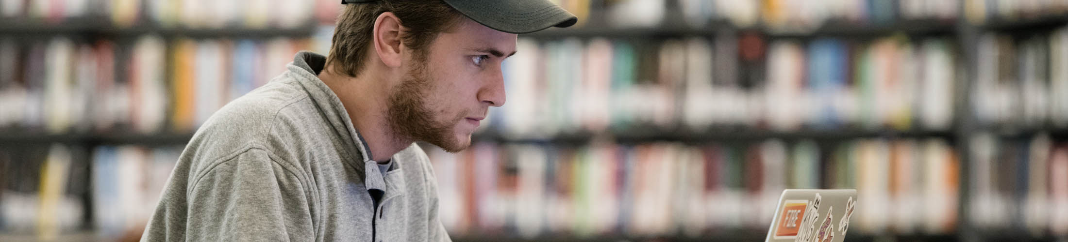 Male student working on laptop in library.