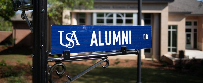 Alumni Drive street sign in front of the Alumni Center