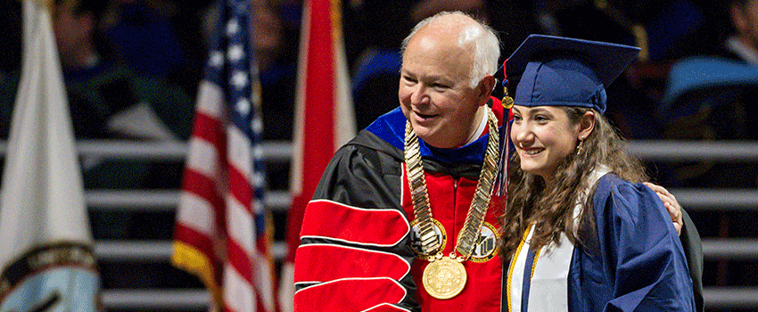 Graduate showing thumbs up walking to graduation