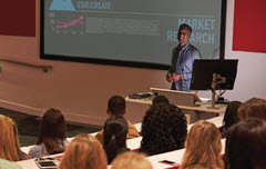 Man in front of class with sceen behind him