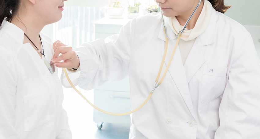 Nurse listening to heart of patient with stethoscope.